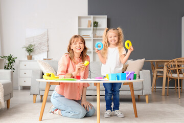 Wall Mural - Nanny and little girl playing with toys on table at home