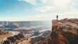 Person standing on cliff edge overlooking vast canyon under blue sky