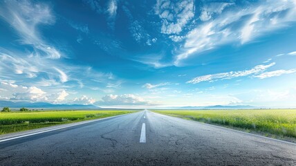 Empty road stretching into distance under vibrant blue sky with fluffy clouds