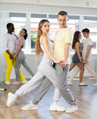 Wall Mural - Couple of young guy and young woman dancing latin dances in studio