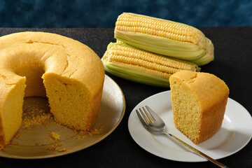 Wall Mural - Corn cake on a plate on a black base, ears of green corn on the table, black table