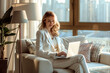 © 수동 김 - A woman in casual business attire sitting on the sofa of her modern apartment, working from home on her laptop and smiling at the camera