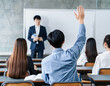 授業中に手を挙げて教師の質問に答える大学生の後ろ姿