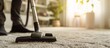 A person diligently cleaning the carpet with a vacuum cleaner, removing dirt and dust particles effortlessly