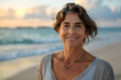 Portrait of a smiling mature woman standing on the beach on a sunny day, enjoying the beauty of nature and relaxation.