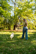 Pretty blonde girl walking her dog in the park , vertical image 