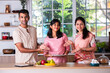 Cute little indian master chef with young parents in the kitchen making cake