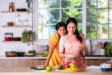 indian mother daughter cooking in kitchen