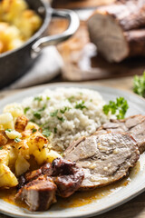 Wall Mural - A portion of baked juicy neck on a plate with a side dish of potatoes and rice and a sauce with baked goods