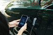 Woman controlling electric car charging level via mobile app