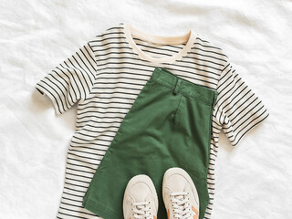 Wall Mural - Women's clothing - bermuda cotton shorts, striped t-shirt and textile sneakers on a light background, top view