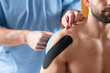 Elastic therapeutic tape application on the shoulder for support and rehabilitation.