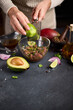 Woman grates lime zest onto chopped tuna, cilantro and onion in a glass bowl cooking traditional tuna tartare
