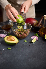 Canvas Print - Woman grates lime zest onto chopped tuna, cilantro and onion in a glass bowl cooking traditional tuna tartare