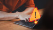 A caution warning sign alerts the user while using a computer laptop, emphasizing the importance of cyber security in detecting viruses, protecting personal data, and maintaining network security.