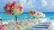Elegant wedding table arrangement with vibrant flowers by the sea.
