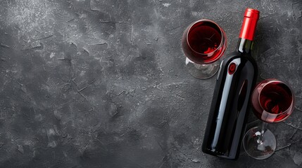 Wall Mural - Red wine glasses and bottle on stone background. Top view with copy space