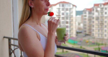 Wall Mural - A woman drinking a delicious green smoothie on the terrace at home