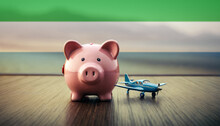 A Piggy Bank With An Airplane Against The Backdrop Of The Sierra Leone Flag. Saving Money For Vacations, Leisure, And Flights.
