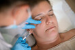 Faceless cosmetologist administering facial rejuvenating injection to client