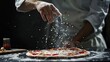 Chef sprinkles cheese on pizza to serve to customer on dark background