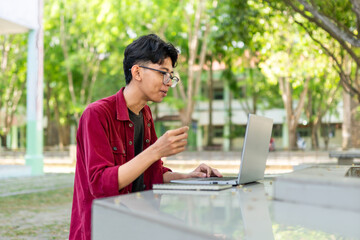 Young Asian man smiling while using laptop for working and video conference meeting at the morning. Asian man having a video call on laptop. Concept of remote and freelance 