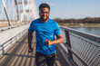 Young african-american man is jogging on the bridge in the city.