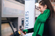 © Westend61 - Smiling woman buying ticket through smart phone at train station