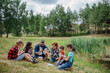 © Halfpoint - Teacher showing sample of lake water to school children, during field teaching class. Outdoor active education helping young student to learn about ecosystem.