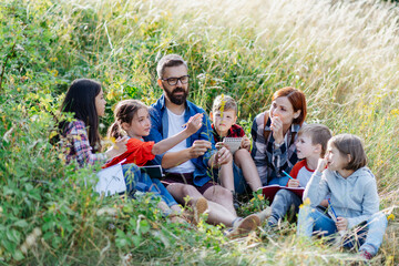 Canvas Print - Young students learning about nature, forest ecosystem during biology field teaching class, observing wild plants, taking notes. Dedicated teachers during outdoor active education.