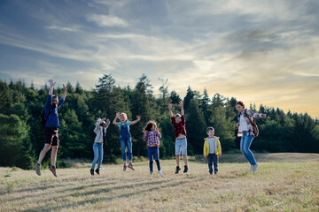 Sticker - Students and teachers jumping on meadow during biology field teaching class, holding hands. Dedicated teachers during outdoor active education teaching about ecosystem, ecology.