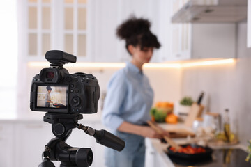 Wall Mural - Food blogger cooking while recording video in kitchen, focus on camera