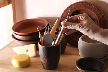 Wall Mural - Woman taking clay crafting tool from cup in workshop, closeup