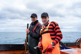 Fototapeta Konie - Fishermen looking at camera working on a lobster fishing boat