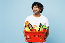Young Indian Man In White T-shirt Casual Clothes Hold Red Basket For Takeaway Mock Up With Food Products Look Aside On Area Isolated On Plain Blue Background Delivery Service From Shop Or Restaurant