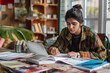 © Татьяна Евдокимова - Engaged Indian student organizes her textbooks while studying in a cozy room with a laptop in front of her