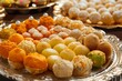 Close-up view of a decorative platter with assorted colorful Indian sweets including ladoos and jalebis