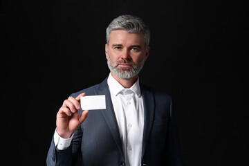 Canvas Print - Handsome businessman holding blank business card on black background