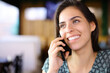 Happy woman in a bar talking on phone with perfect smile