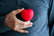 Ein Mann hält ein rotes Herz vor seiner Brust. Gesundheit, Symbol.