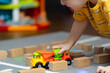 Toddler boy playing with a toy and wooden blocks on the floor in the children's room. Children leisure and lifestyle. Childhood. Focus on the little car