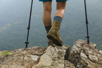Wall Mural - succesful woman hiker legs stand on mountain peak cliff edge