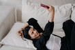 Woman lying on a couch, taking a selfie with her smartphone.