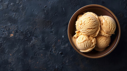 Poster - A bowl of caramel ice cream scoops on a textured dark background