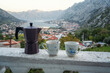 A pair of coffee cups and a coffee maker on the ledge of the terrace of a room with an amazing panoramic view of the picturesque Bay of Kotor and Montenegro