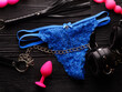 Bright blue panty and different sex toys over black wooden background