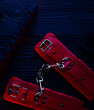 red handcuffs over black wooden backdrop. bdsm background