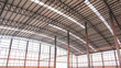 Steel wall framework structure with metal columns and curve roof beams inside of large industrial factory building in construction site, low angle and perspective side view