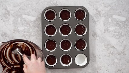 Wall Mural - Flat lay. Scooping chocolate cupcake dough into the cupcake liners.