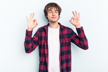 Poster - Young caucasian man isolated on blue background relaxes after hard working day, she is performing yoga.